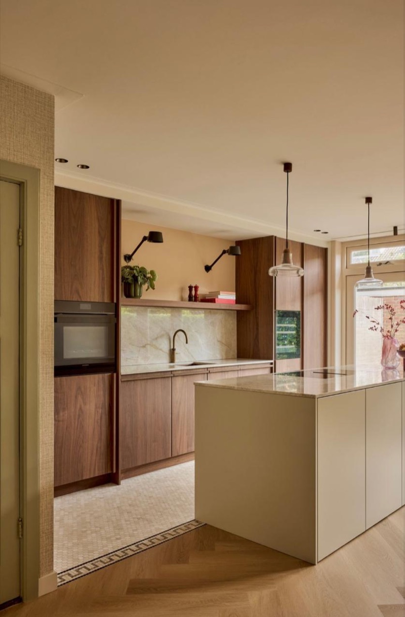 Cocina luminosa con muebles de madera, isla central y suelo de parqué.